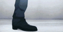 a person wearing a pair of black boots is walking on a white floor .