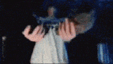 a person in a white dress is holding a gun in their hands in a dark room .