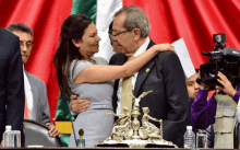 a woman hugging a man in front of a flag