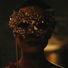 a woman wearing a gold mask with flowers and rhinestones