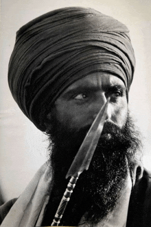 a black and white photo of a man with a beard and turban