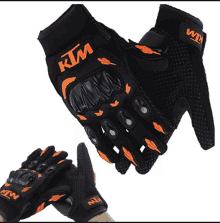 a pair of black and orange ktm motorcycle gloves on a white background