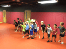 a group of young boys are standing on a red mat and one of them is wearing a red shirt that says 100
