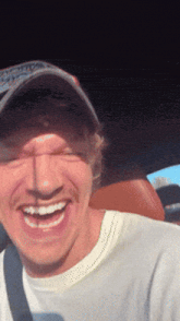 a man wearing a hat and a white shirt is smiling for the camera