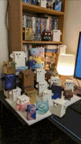 a bunch of boxes with faces on them are on a desk in front of a bookshelf