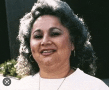 a woman with curly hair and earrings is smiling for the camera .