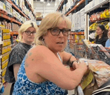 a woman wearing glasses is sitting in a grocery store looking at something