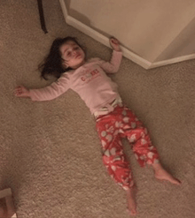 a little girl is laying on the floor wearing a shirt that says cakes
