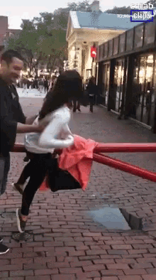 a woman is being held by a man on a brick sidewalk in front of a building with a sign that says salad clips