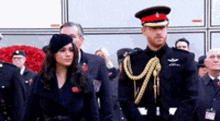 a man and a woman in military uniforms are standing next to each other in front of a crowd .