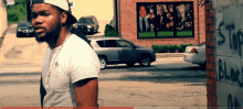 a man standing next to a brick wall that says stop black