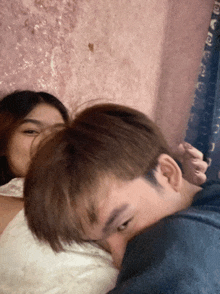 a man and a woman are laying on a bed and the man is covering the woman 's face