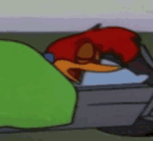 woody woodpecker is sleeping in a bed with a green blanket on it .