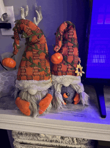 two stuffed gnomes with pumpkins on their hats are sitting on a table