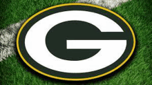 the green bay packers logo is on a field of green grass .