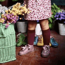 a little girl wearing a skirt and knee high socks is standing in front of a row of shoes .