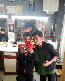 two boys are taking a selfie in a barber shop with a sign on the wall that says açik