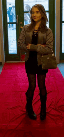 a woman standing on a red carpet holding a purse that says ck on it
