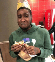 a man wearing a burger king crown is eating a burger