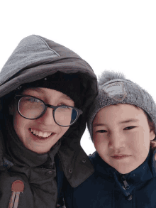 a boy with glasses and a boy with a hat that says ' north face ' on it