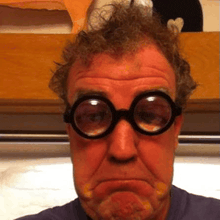 a close up of a man wearing glasses making a funny face .