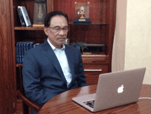 a man sitting at a table with an apple laptop