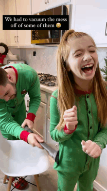 a girl is laughing while a man vacuums the mess off of her hair