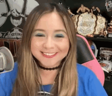 a woman is smiling in front of a microphone while sitting in front of a shelf with wrestling trophies .