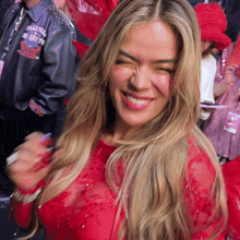 a woman wearing a red dress is smiling and making a funny face .