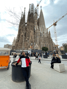 a man stands in front of a large building with a sign that says ' sagrada familia ' on it