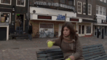 a woman sits on a bench in front of a building that has a sign on it that says ' apollo '