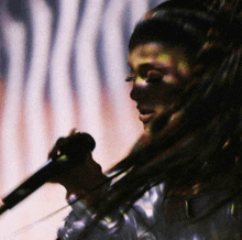 a woman is singing into a microphone in front of a curtain