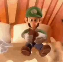 a cartoon character in a green hat is sitting on a bed holding a book .