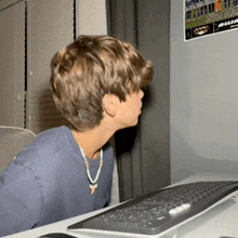 a young boy is looking at a computer screen with a poster on the wall above him