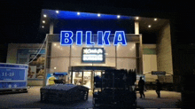 the front of a store called bilka is lit up at night