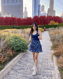 a woman in a blue skirt is standing on a brick walkway