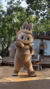 a stuffed animal in a bunny costume is standing on a stage in front of a crowd .