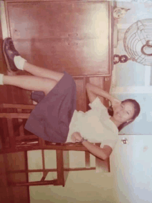 a girl in a white shirt and blue skirt laying on a table