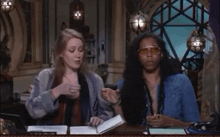 a man and a woman sit at a table with a book
