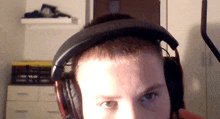 a man wearing headphones looks at the camera with a shelf of books in the background