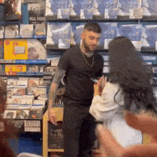 a man in a black shirt is talking to a woman in a store with a sign that says realfriends