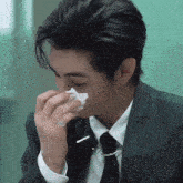 a man in a suit and tie is blowing his nose with a napkin