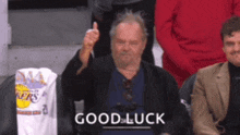 a man is giving a thumbs up while sitting in a stadium with the words good luck written on the bottom