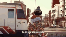 a woman hugging another woman in front of a train with the words va en tren a la mascleta above her