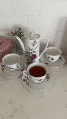 a tea set with two cups and saucers and a teapot with pink flowers on it