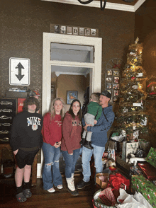 a family posing for a picture in front of a christmas tree and a sign that says bb