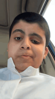 a young boy in a white shirt is sitting in the back seat of a car