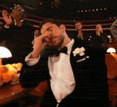 a man in a tuxedo with a white flower in his pocket is covering his eyes
