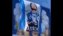 a blue and white flag with a drawing of a man and the word assim on it