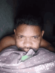 a man with a beard is laying under a blanket that says april fool